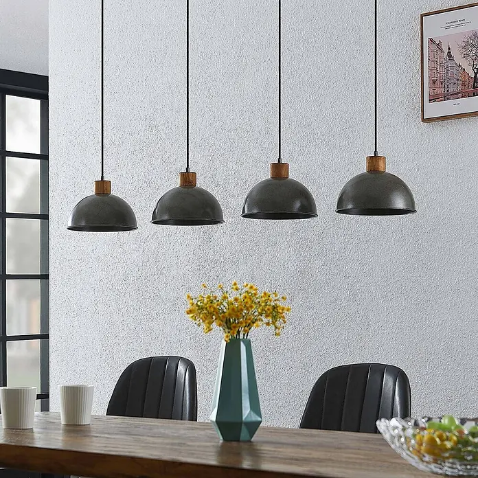 Lindby Pendelleuchte Durbis - L x B x H: 116 x 25 x 180 cm, schwarz, Holz natur, dunkelgrau, E27 - Vier dunkelgraue Metall-Pendelleuchten mit Holzdetails hängen über einem Esstisch und beleuchten den Raum.
