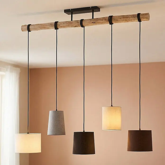Lindby Pendelleuchte Amilia - Multicolour, Holz natur, Schwarz, grau, beige, braun, weiß, E27 - Eine rustikale Deckenleuchte mit Holzbalken und fünf schwarzen Pendelleuchten mit Stoffschirmen in neutralen Tönen, die einen Raum beleuchten.