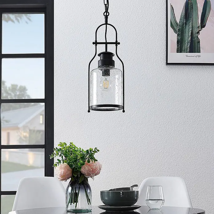 Lindby Pendelleuchte Rozalie - L x B x H: 18 x 18 x 21 cm, Schwarz matt, klar, E27 - Schwarze industrielle Pendelleuchte mit klarem, blasigem Glasschirm, über einem Esstisch in einem modernen Raum.