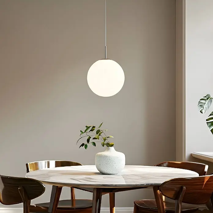 Lindby Pendelleuchte Marike - L x B x H: 40 x 40 x 150 cm, weiß / opal, weiß, nickel satiniert, E27 - Eine kugelförmige weiße Glaspendelleuchte hängt über einem modernen Esstisch und beleuchtet den Bereich.