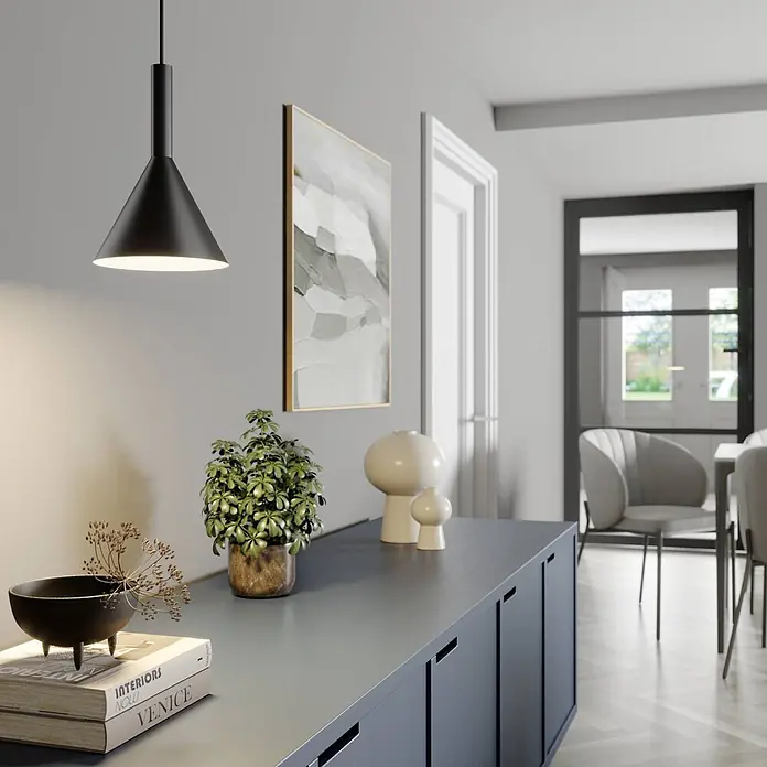Arcchio Pendelleuchte Tadej - schwarz, Schwarz, weiß, E27 - Schwarze konische Pendelleuchte beleuchtet ein modernes graues Sideboard mit Deko in einem Wohnraum.