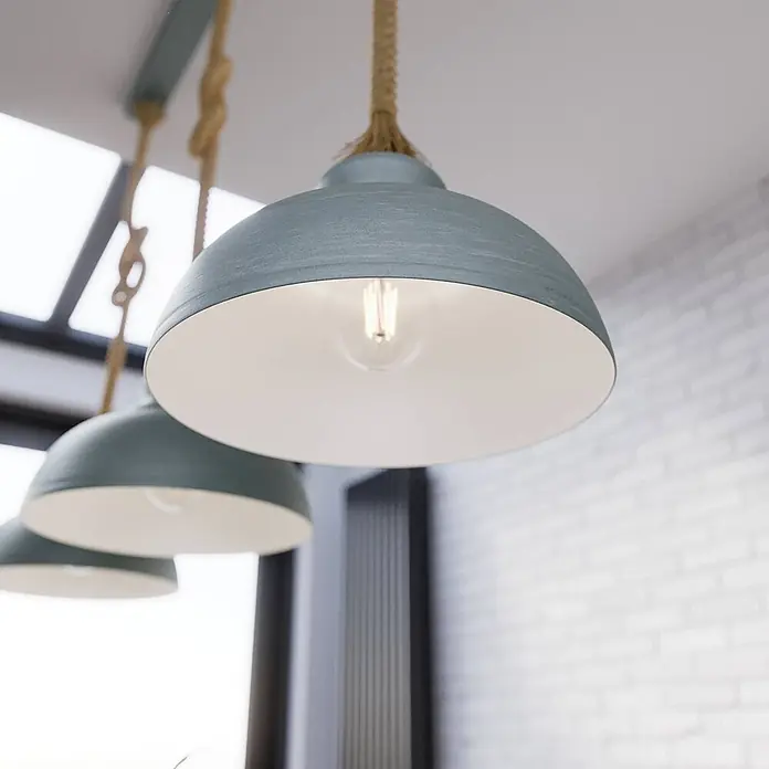 Lindby Pendelleuchte Chaby - alu / grau / zink, beton, E27 - Drei blau-graue Metall-Pendelleuchten mit Seilaufhängung hängen von der Decke, die vorderste ist beleuchtet.