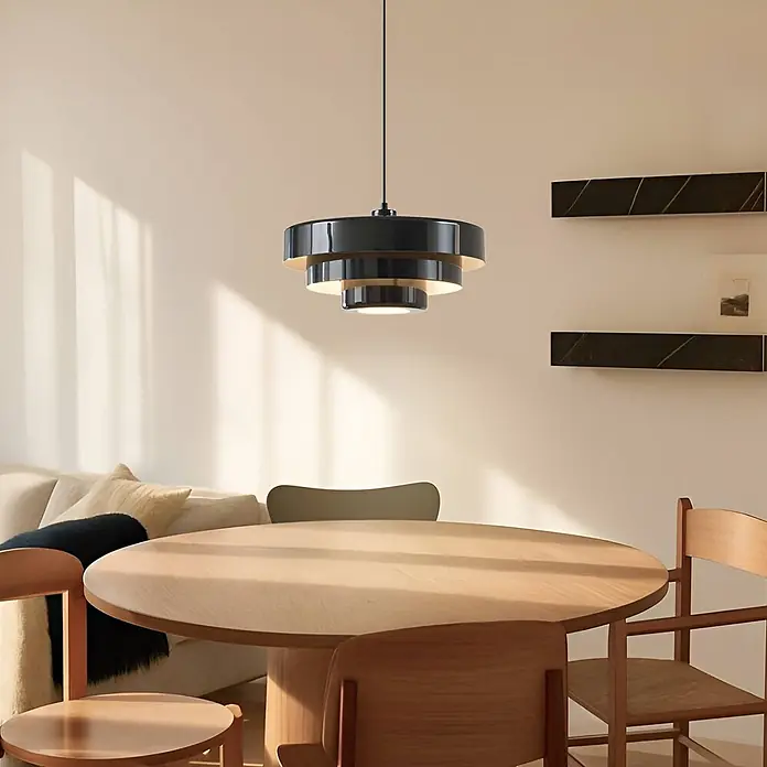Lindby Pendelleuchte Tivra - schwarz, Schwarz, E27 - Schwarze und goldene Hängelampe in Etagenform über einem runden Holztisch in einem modernen Esszimmer.