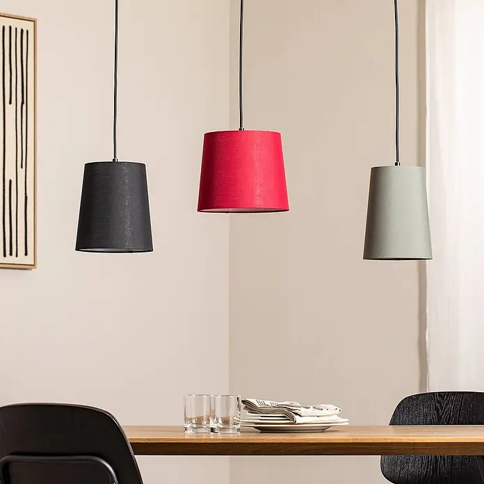 Lindby Pendelleuchte Amilia - L x B x H: 90 x 23 x 180 cm, Multicolour, Holz natur, Rot, grau, Schwarz, E27 - Drei Pendelleuchten aus Stoff in Schwarz, Rot und Salbeigrün hängen über einem Esstisch aus Holz.