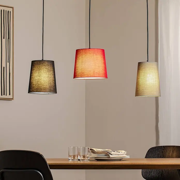 Lindby Pendelleuchte Amilia - L x B x H: 90 x 23 x 180 cm, Multicolour, Holz natur, Rot, grau, Schwarz, E27 - Drei Hängeleuchten aus Stoff in Schwarz, Rot und Beige hängen über einem Holzesstisch und beleuchten ihn.