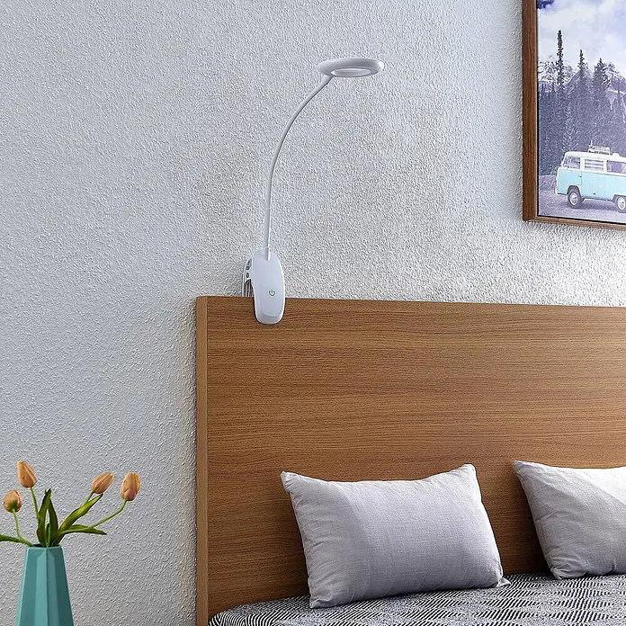 Prios Klemmleuchte Harumi - Farbe Gehäuse: weiß / opal - Weiße, flexible Klemmlampe mit Ringlicht, als Nachttischlampe an einem Holzbetthaupt befestigt.