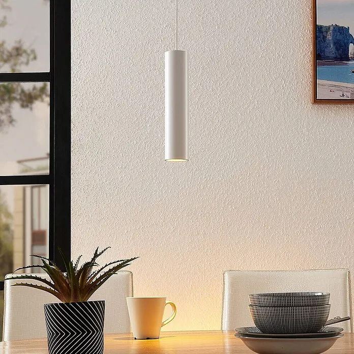 Arcchio Pendelleuchte Ejona - L x B x H: 6 x 6 x 27 cm, weiß / opal, weiß, GU10 - Weiße zylindrische Pendelleuchte hängt über einem Tisch.
