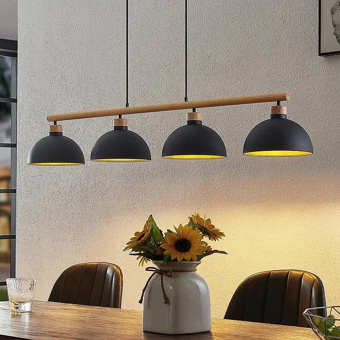 Lindby Pendelleuchte Tirzana - schwarz, Schwarz, gold, holz hell, E27 - Vierflammige Pendelleuchte mit schwarzen Metallschirmen und Holzstange über einem Esstisch.
