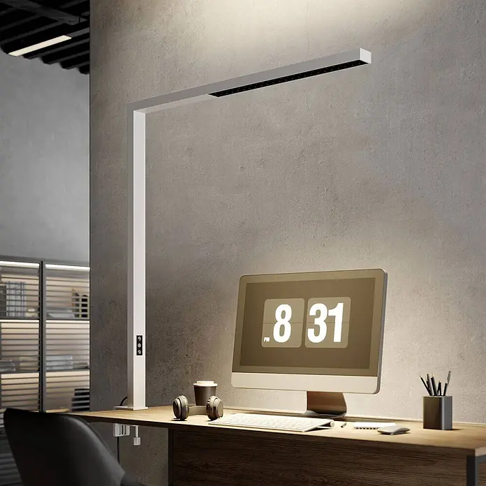 Arcchio Klemmleuchte Jolinda - Farbe Gehäuse: weiß / opal - Weiße L-förmige Schreibtischlampe mit linearer Lichtleiste, an einem Holzschreibtisch befestigt und einen modernen Computerarbeitsplatz beleuchtend.