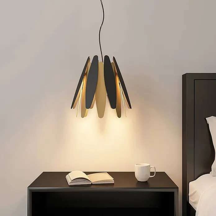 Lucande Pendelleuchte Lounit - schwarz, Schwarz, gold, E27 - Moderne schwarz-goldene Pendelleuchte über einem Nachttisch, beleuchtet Buch und Tasse.
