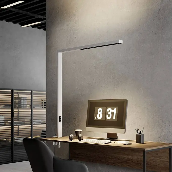 Arcchio Klemmleuchte Jolinda - Farbe Gehäuse: weiß / opal - Weiße, lineare LED-Schreibtischlampe beleuchtet einen modernen Schreibtisch mit Computer und Büroaccessoires.