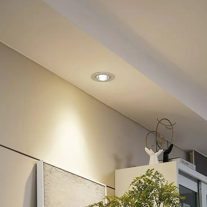 Lindby Einbauleuchte Jyla - weiß / opal - Silberne Einbauleuchte in weißer Decke, beleuchtet die darunterliegende Wand mit warmem Licht.