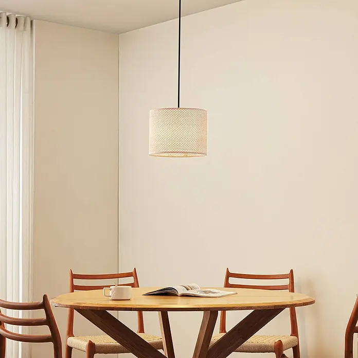 Lindby Pendelleuchte Soula - creme / amber, beige, E27 - Zylindrische geflochtene Pendelleuchte mit hellem Schirm über einem Holzesstisch.