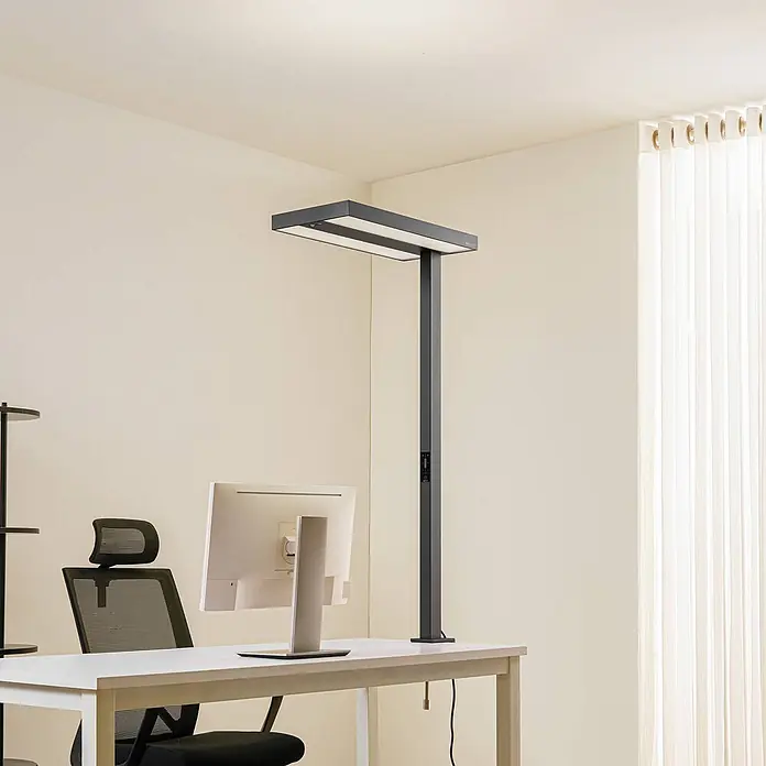 Arcchio Klemmleuchte Logan - Farbe Gehäuse: schwarz - Dunkelgraue Schreibtischlampe mit zwei rechteckigen Lichtpaneelen, auf einem weißen Schreibtisch neben einem Computermonitor.