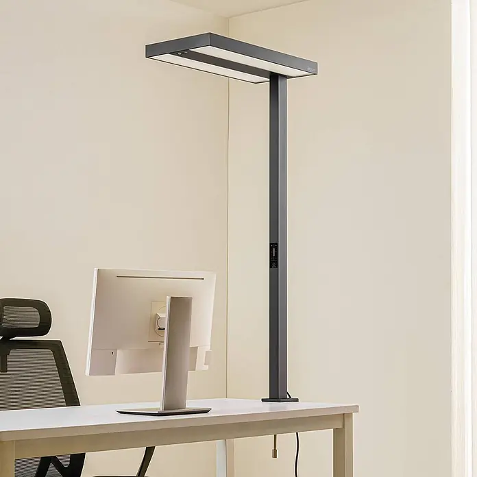 Arcchio Klemmleuchte Logan - Farbe Gehäuse: schwarz - Hohe, dunkelgraue rechteckige Schreibtischlampe beleuchtet einen modernen Bürotisch mit Monitor und Stuhl.