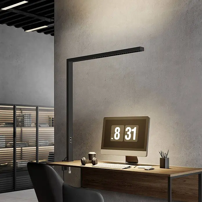 Arcchio Klemmleuchte Jolinda - Farbe Gehäuse: schwarz - Moderne schwarze LED-Schreibtischlampe beleuchtet einen zeitgenössischen Home-Office-Schreibtisch mit Monitor und Bürozubehör.