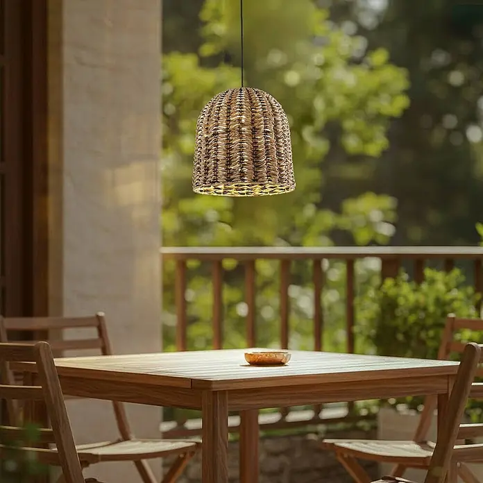 Lindby Außenwand- & Deckenleuchte Taryn - L x B x H: 35 x 35 x 35 cm, Holz hell, IP44 - Eine natürliche geflochtene Pendelleuchte erhellt einen Holztisch im Freien auf einer Terrasse.