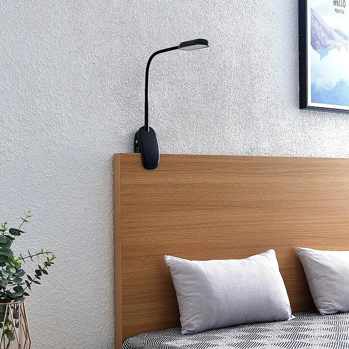 Prios Klemmleuchte Najari - Farbe Gehäuse: schwarz - Schwarze Klemmleuchte mit flexiblem Arm und länglichem Leuchtkopf, an Holz-Kopfteil über einem Bett befestigt.