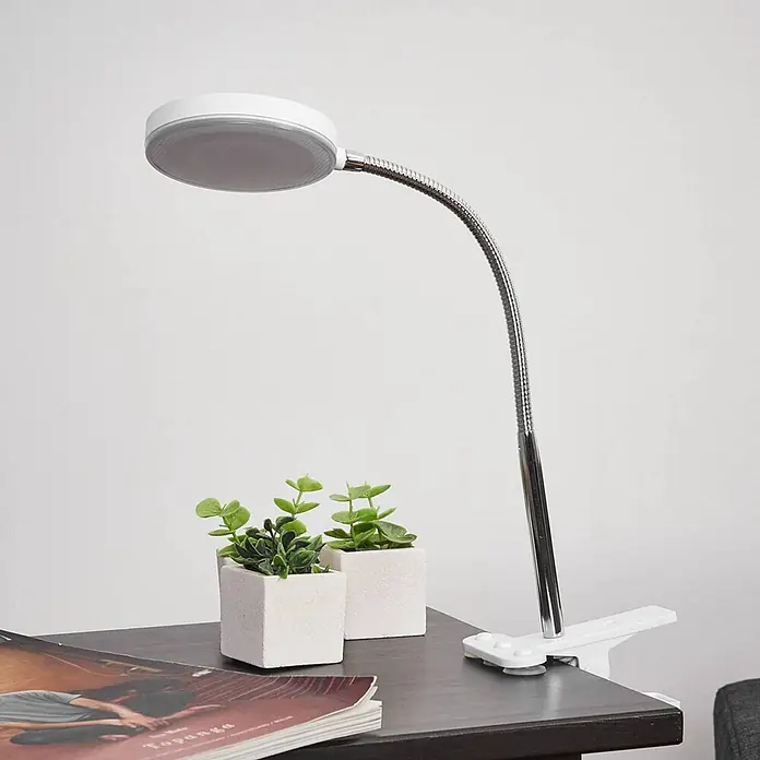 Lindby Klemmleuchte Milow - L x B x H: 11,3 x 10 x 36 cm, Farbe Gehäuse: weiß / opal - Weiße LED-Klemmleuchte mit flexiblem silbernem Hals, beleuchtet einen dunklen Tisch.
