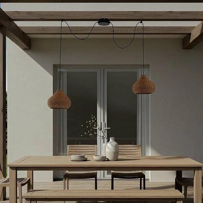 Lucande Außenwand- & Deckenleuchte Taniola - L x B x H: 100 x 30 x 24 cm, Holz hell, IP44 - Zwei braune Hängelampen aus geflochtenem Rattan mit schwarzen Kabeln über einem hölzernen Esstisch im Freien.