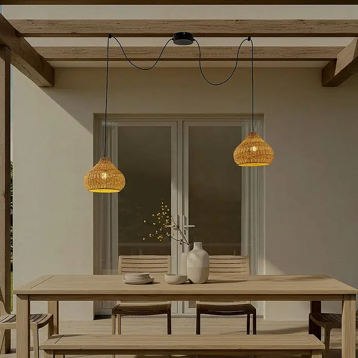 Lucande Außenwand- & Deckenleuchte Taniola - L x B x H: 100 x 30 x 24 cm, Holz hell, IP44 - Zwei geflochtene Rattan-Pendelleuchten mit schwarzen Kabeln beleuchten einen Essbereich im Freien über einem Holztisch.