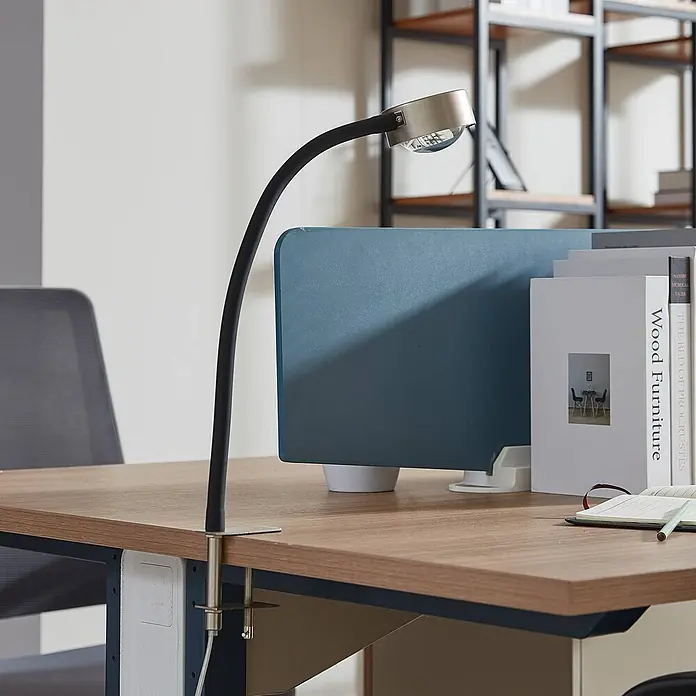 Lindby Klemmleuchte Jyla - L x B x H: 34,2 x 8 x 25 cm, Farbe Gehäuse: alu / grau / zink - Klemm-Schreibtischlampe mit schwarzem flexiblem Arm und silberfarbenem Kopf, an einem Holzschreibtisch befestigt.