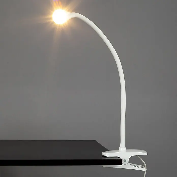 Lindby Klemmleuchte Baris - L x B x H: 13 x 6 x 44 cm, Farbe Gehäuse: weiß / opal - Weiße Klemmleuchte mit flexiblem Hals und leuchtender Glühbirne, an einem dunklen Schreibtisch befestigt.