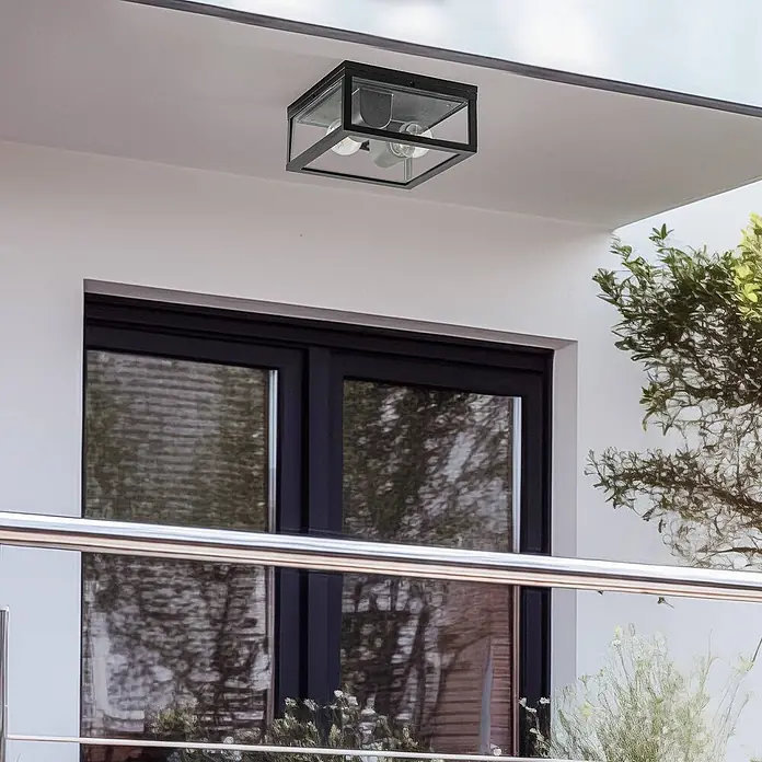 Lindby Außenwand- & Deckenleuchte Kremena - schwarz, klar / transparent, IP44 - Schwarze quadratische Aufputz-Außenleuchte mit Klarglas, an Balkondecke montiert. Enthält zwei Glühbirnen.