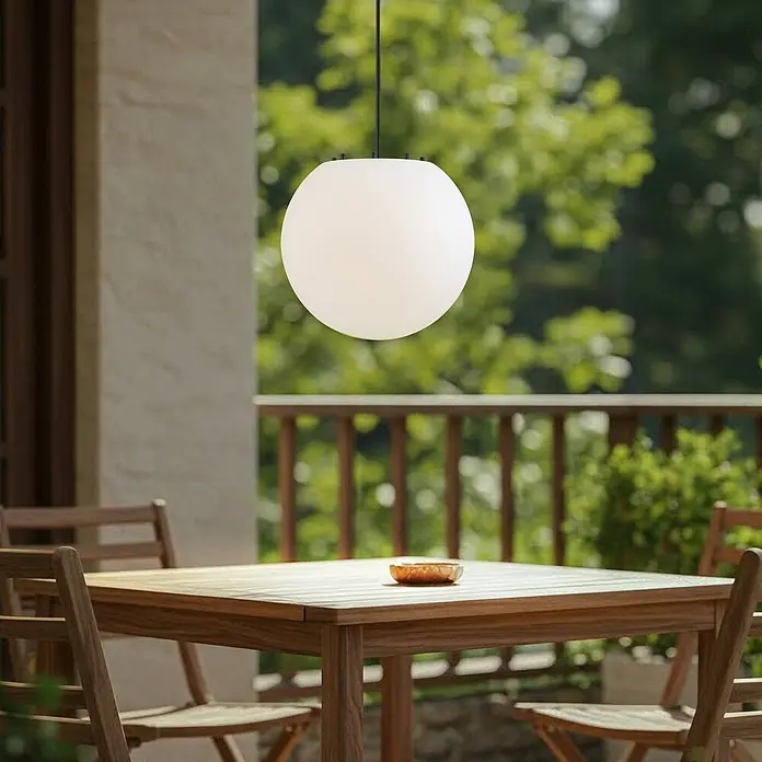 Lindby Außenwand- & Deckenleuchte Alea - weiß / opal, IP44 - Weiße Opalglas-Kugelhängeleuchte über einem Holztisch auf der Terrasse.