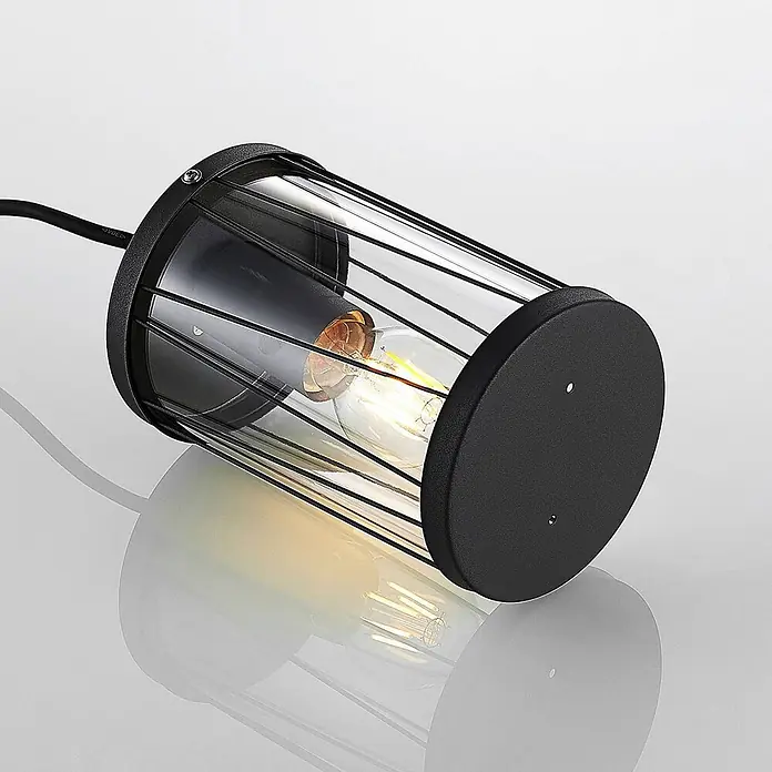 Lindby Außenwand- & Deckenleuchte Yonan - schwarz, schwarz, IP44 - Schwarze zylindrische Außenleuchte mit klarem Glasschirm, Metallgitter und sichtbarer Glühbirne.