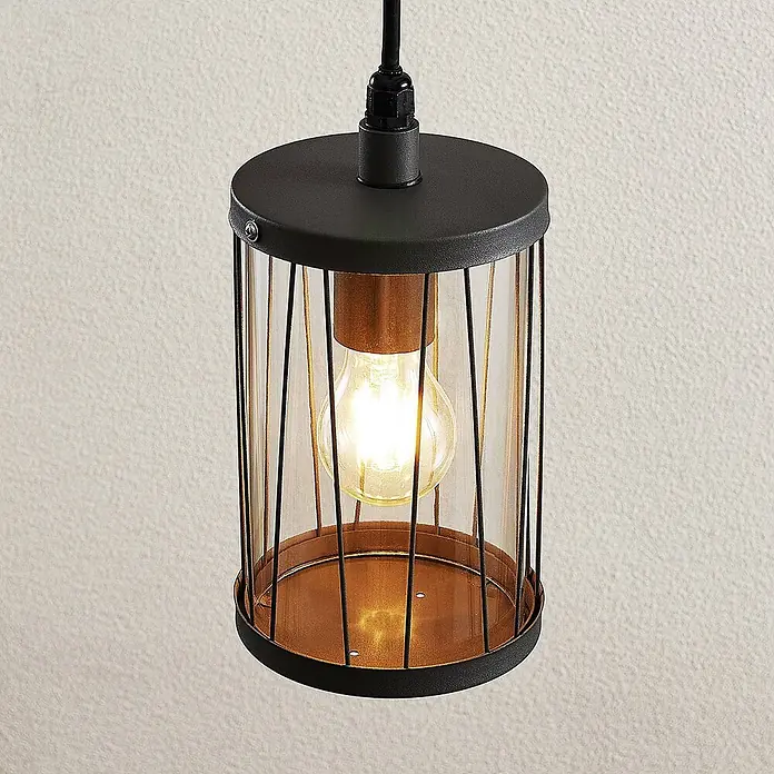 Lindby Außenwand- & Deckenleuchte Yonan - schwarz, schwarz, IP44 - Zylindrische Pendelleuchte mit schwarzem Metallgitter, klarem Glas und Kupferakzent, mit leuchtender Glühbirne.