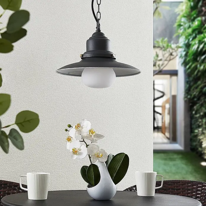 Lindby Außenwand- & Deckenleuchte Roisin - alu / grau / zink, alu / grau / zink, IP44 - Schwarze Outdoor-Pendelleuchte mit breitem Metallschirm und weißem Kugeldiffusor, über einem Terrassentisch hängend.