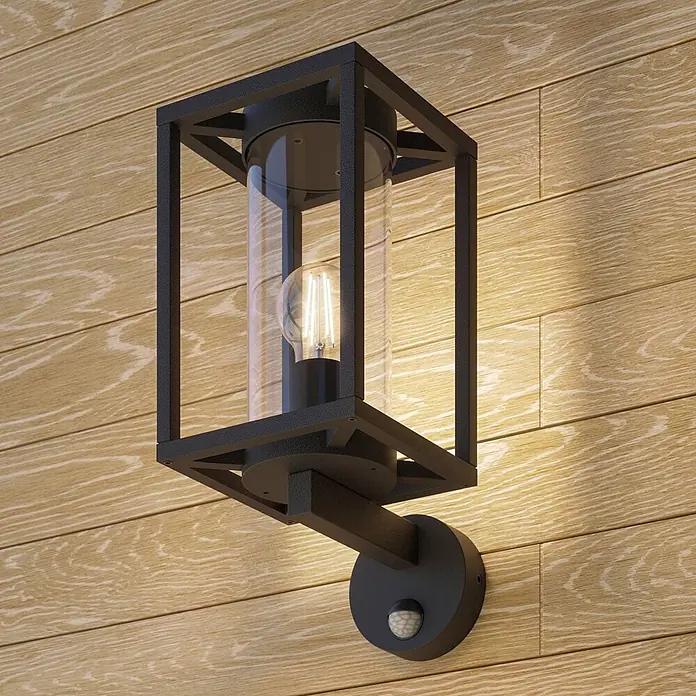 Lucande Außenwandleuchte Ferda - schwarz, schwarz, IP44 - Schwarze Metall-Außenwandleuchte mit Klarglas und LED-Glühbirne, Bewegungssensor, an Holzwand montiert.