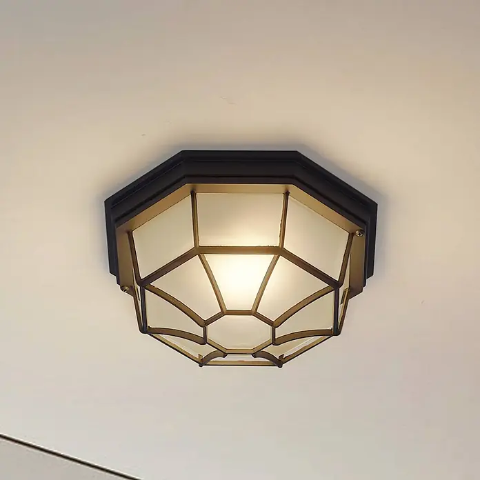 Lindby Außenwand- & Deckenleuchte Idril - schwarz, IP44 - Achteckige Deckenleuchte mit dunklem Rahmen und goldenem Geometriegitter über mattierten Glasscheiben, beleuchtet.
