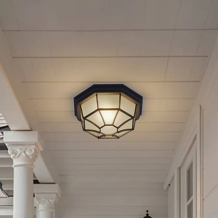 Lindby Außenwand- & Deckenleuchte Idril - schwarz, IP44 - Dunkle achteckige Deckenleuchte mit mattem Glas und geometrischem Gitter an einer weißen Verandadecke.