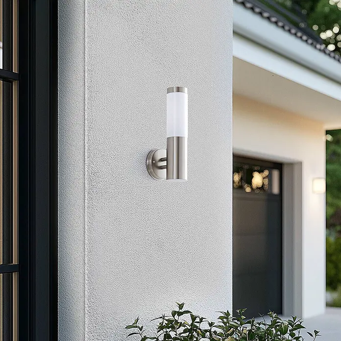 Lindby Außenwandleuchte Kristof - alu / grau / zink, alu / grau / zink, IP44 - Moderne zylindrische Außenwandleuchte aus gebürstetem Edelstahl mit weißem Diffusor, an einer strukturierten Hauswand montiert.