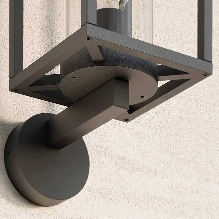 Lucande Außenwandleuchte Ferda - schwarz, schwarz, IP44 - Dunkelgraue Wandleuchte aus Metall mit quadratischem Käfigdesign und klarem Glaszylinder, montiert.