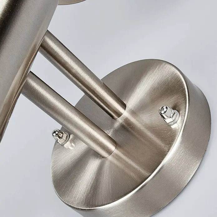 Lindby Außenwandleuchte Nada - 23 x 20 x 33,5 cm, alu / grau / zink, IP44 - Nahaufnahme einer runden Leuchtenbasis aus gebürstetem Metall mit zwei Armen und Zierschrauben.