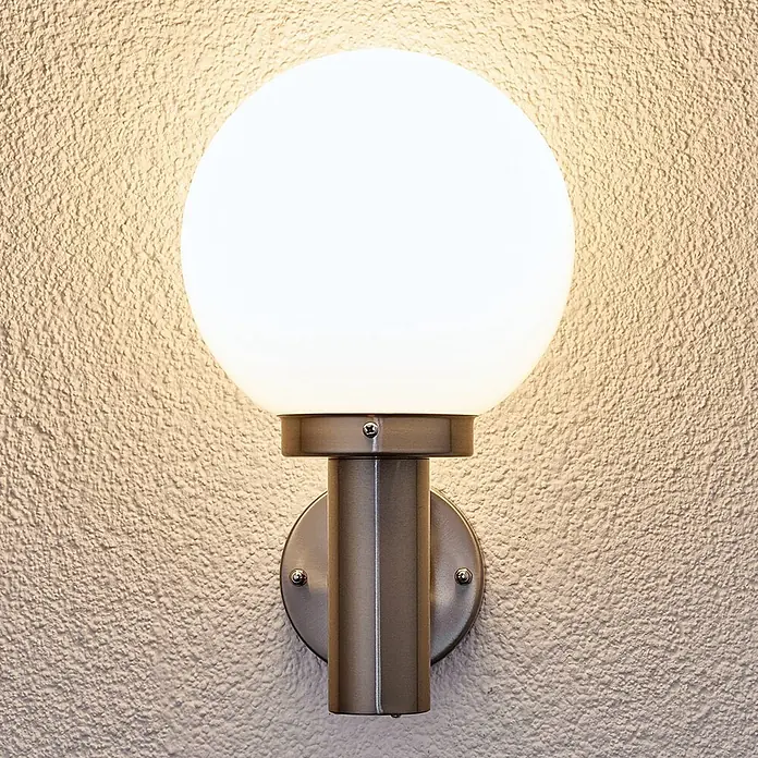 Lindby Außenwandleuchte Nada - alu / grau / zink, IP44 - Sphärische weiße Wandlampe mit gebürstetem Metallsockel, an einer strukturierten Wand montiert.