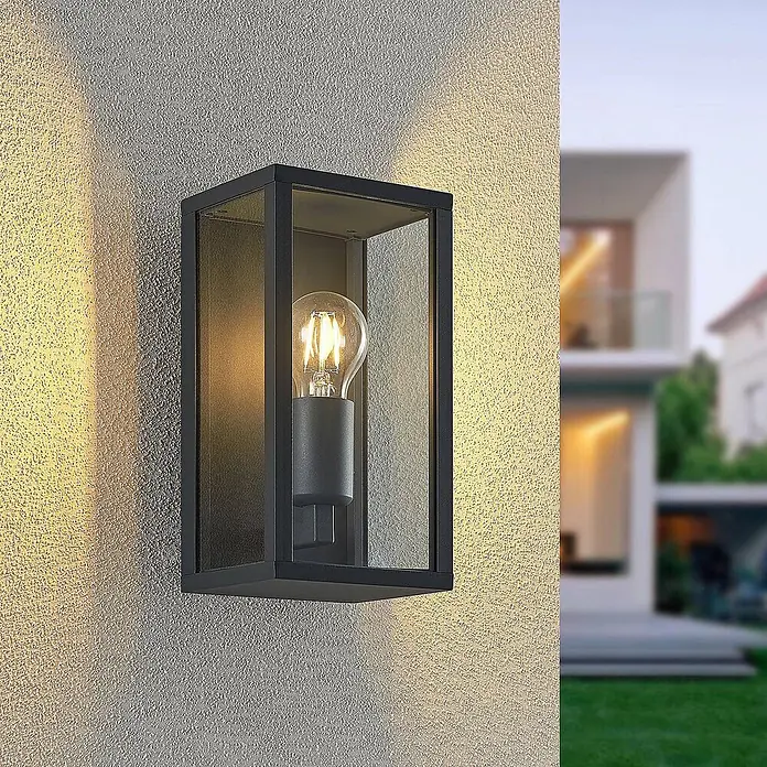 Lindby Außenwandleuchte Peldar - schwarz, IP44 - Moderne schwarze Außenwandleuchte mit warmweißer LED-Glühfadenlampe, die eine strukturierte Wand beleuchtet.