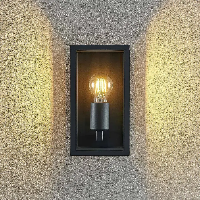 Lindby Außenwandleuchte Peldar - schwarz, IP44 - Schwarze rechteckige Außenwandleuchte mit Vintage-LED-Birne, wirft warmes Licht auf eine strukturierte Wand.