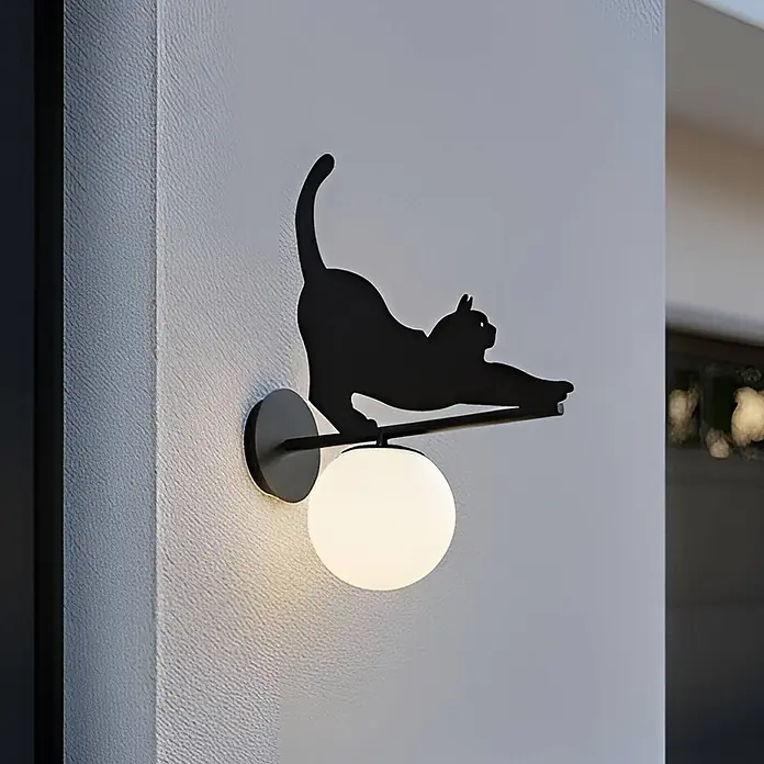 Lindby Außenwandleuchte Katti Cat - 45 x 15 x 40 cm, schwarz, weiß / opal, IP44 - Wandleuchte aus schwarzem Metall mit einer sich reckenden Katzensilhouette über einer weißen Kugel-LED-Lampe.
