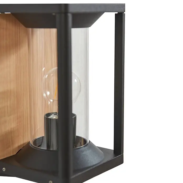 Lucande Außenwandleuchte Candina - 20 x 14,6 x 27,6 cm, schwarz, klar / transparent, IP65 - Schwarze Metall-Wandleuchte mit klarem Glaszylinder und sichtbarer Glühbirne, auf Holz montiert.