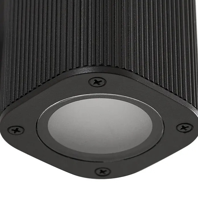 Lindby Außenwandleuchte Halvar - 8 x 11 x 20,5 cm, schwarz, klar / transparent, IP65 - Schwarze gerippte zylindrische Außenleuchte mit quadratischem Sockel und kreisförmiger Lichtquelle, befestigt mit vier Kreuzschlitzschrauben.