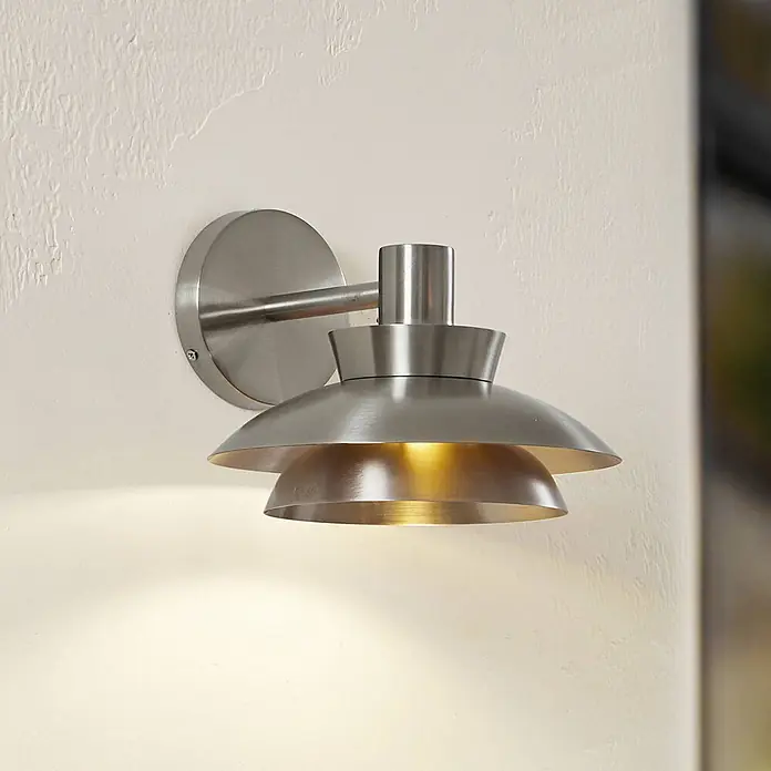 Lucande Außenwandleuchte Thais - alu / grau / zink, IP44 - Gebürstete Metall-Wandleuchte mit gestuftem Schirm an strukturierter Wand, spendet warmes Licht.
