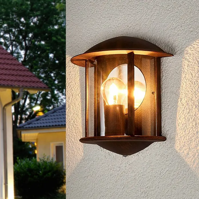 Lindby Außenwandleuchte Maelis - braun / rost, IP44 - Dunkelbronzene Außenwandleuchte mit Glas, an einer strukturierten Wand montiert, spendet warmes Licht.
