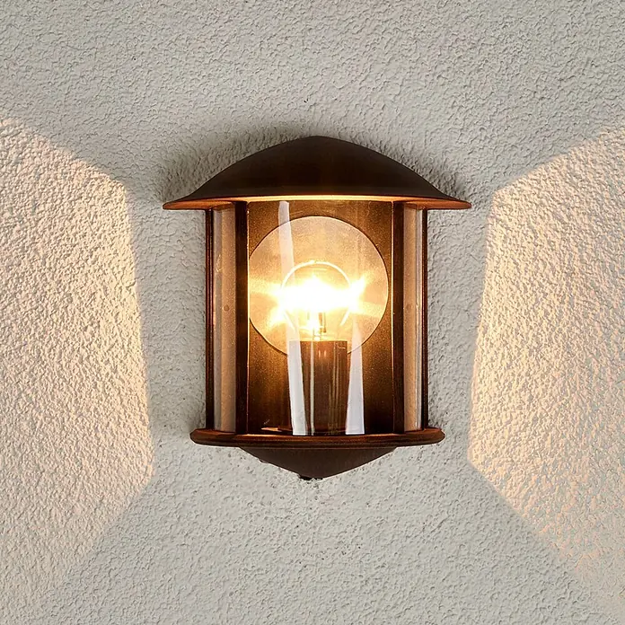 Lindby Außenwandleuchte Maelis - braun / rost, IP44 - Dunkle Metall- und Glas-Außenwandleuchte, beleuchtet und an einer strukturierten Wand montiert.