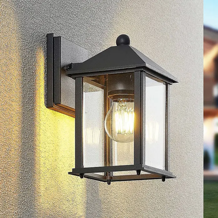 Lindby Außenwandleuchte Giavanna - 18,2 x 14 x 23,3 cm, schwarz, schwarz, IP43 - Schwarze Außenwandlaterne mit Klarglas und LED-Glühfadenlampe, beleuchtet eine strukturierte Wand.