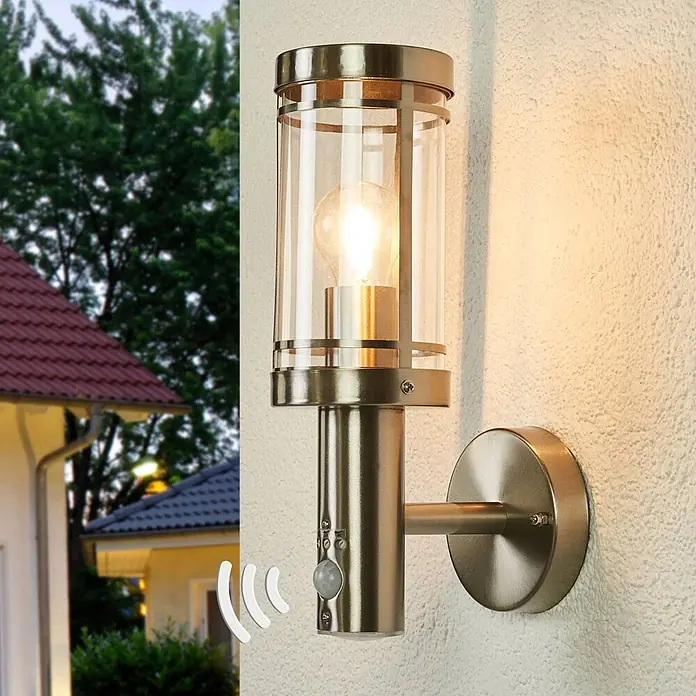 Lindby Außenwandleuchte Djori - alu / grau / zink, IP44 - Gebürstete Metall-Außenwandleuchte mit Klarglas, sichtbarer Birne und Bewegungssensor an einer strukturierten Fassade.