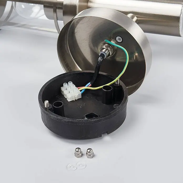 Lindby Außenwandleuchte Djori - alu / grau / zink, IP44 - Offener Sockel einer gebürsteten Metallleuchte, zeigt interne Verkabelung mit Klemmenblock, Muttern und Unterlegscheiben.